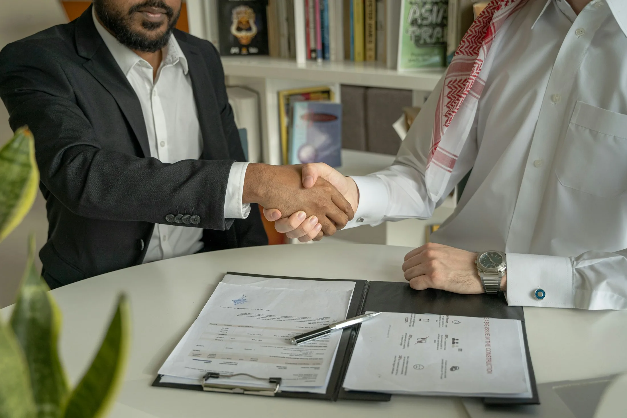 Two businessmen shaking hands over a signed agreement
